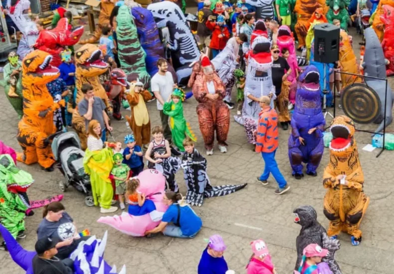 A crowd of people in dinosaur costumes celebrating a Guinness World Record in Vernal, Utah